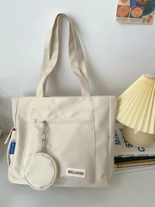 Detail of off-white canvas tote bag with matching round coin purse and logo label