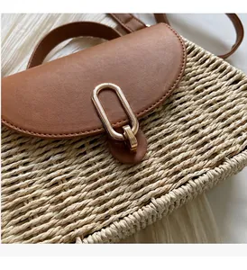 Close-up of handmade straw bag featuring a brown leather lid and gold oval metal lock