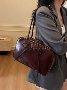 Deep wine red bow shoulder bag with glossy leather finish and dual straps in a modern style