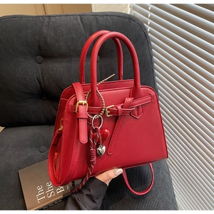 Dettaglio della borsa da sposa in pelle rossa opaca con elegante ciondolo a cuore accessorio