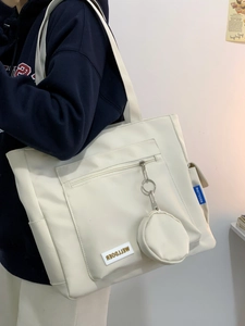 Detail of white nylon tote bag with METTDOER label and matching small hanging pouch