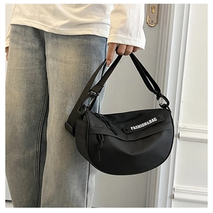 Detail of adjustable wide shoulder strap on a black nylon crescent saddle bag