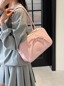 Pale pink large capacity shoulder bag with bow detail shown on a female model