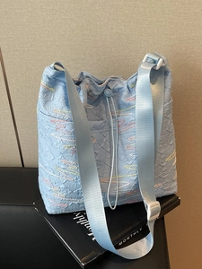 Light blue pleated canvas bucket bag with colorful stitching and adjustable strap
