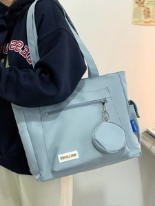Detail of light blue canvas tote bag with multi-pockets and a round mini hanging pouch