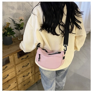 Pink nylon saddle bag detail featuring black wide shoulder strap and brand label