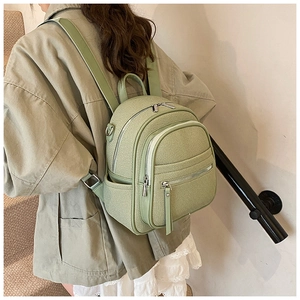 Rear view of a model wearing a light olive green knit mini backpack with leather trim