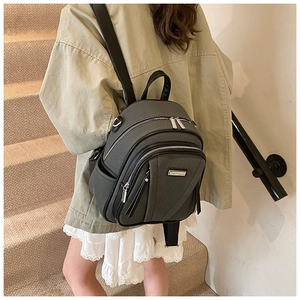 Close-up of dark grey canvas backpack with leather trim and multiple zipper pockets