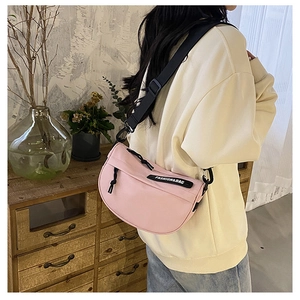 Pink nylon crescent crossbody bag with black adjustable strap shown in a lifestyle setting