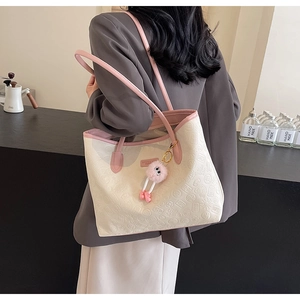 Detail of cream tote bag with embossed floral texture and pink plush pendant