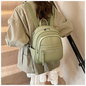 Detail of light green mini backpack featuring woven texture and silver metal zippers