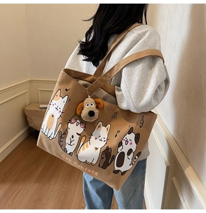 Detailed view of canvas tote bag with cat illustrations and plush puppy charm accessory