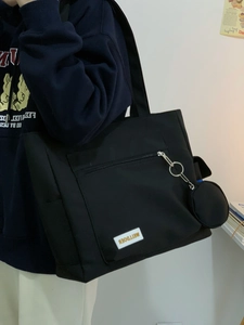 Detail of black canvas tote bag with metal ring zipper and round coin pouch charm
