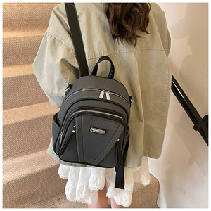 Detail of grey textured mini backpack with black leather straps and silver hardware