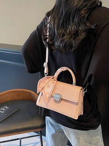 Sac à bandoulière rose contrasté avec texture tissée et foulard cœur sur le modèle