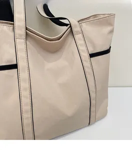 Detail der weichen Canvas-Tasche in Creme mit schwarzen Nähten und minimalistischem Design