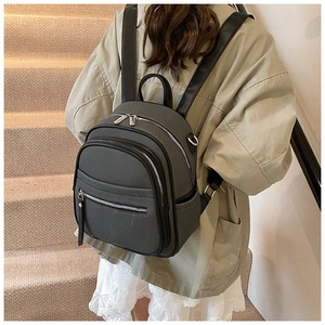 Detailed view of grey leather texture backpack with silver zippers on a model