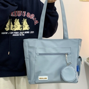 Close-up of light blue nylon tote bag featuring front zip pocket and round coin purse