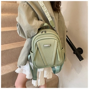 Detail of light green backpack with woven geometric shoulder strap and metal logo plaque