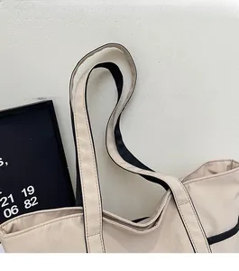 Detail der robusten Doppelriemen an beige Segeltuch-Tasche mit schwarzer Kontrastkante