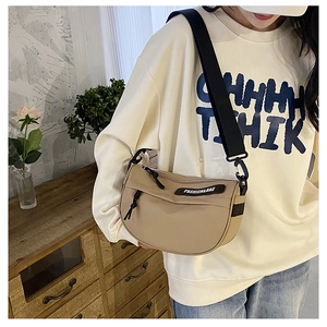 Close-up of khaki nylon crescent saddle bag with wide black strap on female model