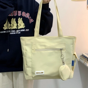Detail of a large cream tote bag featuring front zip pocket and side storage pockets
