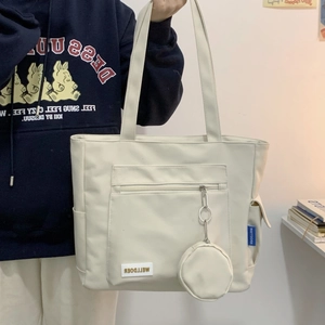 Detail of a large cream tote bag featuring functional exterior pockets and a round coin purse