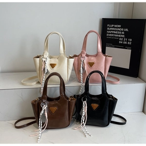 Détail de quatre sacs seau en cuir coloré sur des marches en marbre avec plaques logo