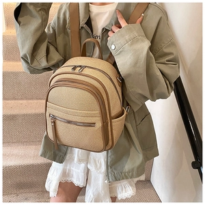 Detail of beige woven mini backpack with brown straps shown on a model on stairs