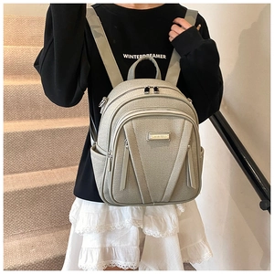 Detailed view of grey backpack with adjustable straps shown in an indoor staircase setting