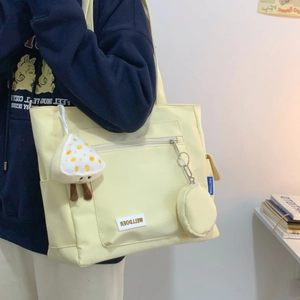 Detailed view of canvas tote bag with mushroom plush pendant and small coin purse attached