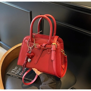 Dettaglio della borsa da sposa rossa con trama in pelle, ciondolo a cuore e tracolla