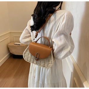 Detail showing back view of woven straw crossbody bag with brown leather strap and handle