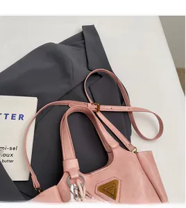 Détail du sac seau rose avec logo triangle doré et accessoire en corde tressée