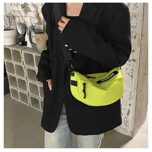 Neon green nylon saddle bag with wide shoulder strap and black fashion label detail