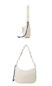 Detail of cream nylon hobo bag featuring ruffled shoulder strap and black bow drawstring