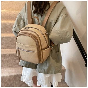 Close-up of beige woven backpack with brown leather trim shown on model back