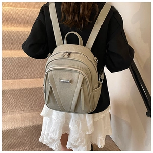 Rear view of minimalist sage green backpack worn by model on carpeted stairs