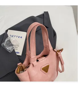 Vue détaillée du sac seau en similicuir rose avec logo triangle doré et bandoulière