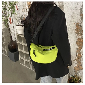 Close-up of neon green nylon saddle bag with wide adjustable strap and black text patch