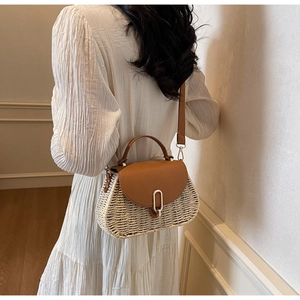 Detail of vintage woven straw crossbody bag with brown leather strap and gold buckle
