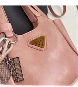 Gros plan d'un sac seau rose avec logo triangulaire en métal et accessoires décoratifs