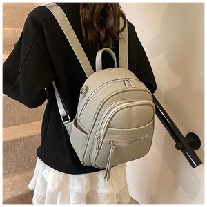 Detail of canvas backpack with woven texture and multi-layer zippers on a model