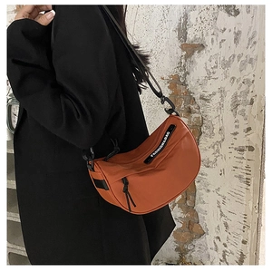 Detail of caramel nylon crescent saddle bag with wide shoulder strap and brand logo