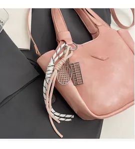 Détail du sac en cuir PU rose avec breloques sur fond de veste de tailleur gris foncé