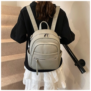 Detail of light grey-green woven texture backpack with silver hardware on model back