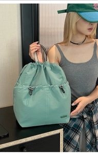 Detail of mint green nylon backpack showing drawstring closure and stitching