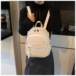 Close-up of beige canvas mini backpack with synthetic leather trim on female model