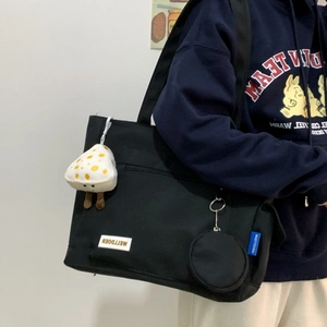 Detail of black canvas tote bag with mushroom plush charm and small round coin purse pouch