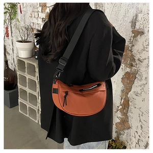 Orange nylon half-moon saddle bag with wide adjustable strap worn on black blazer